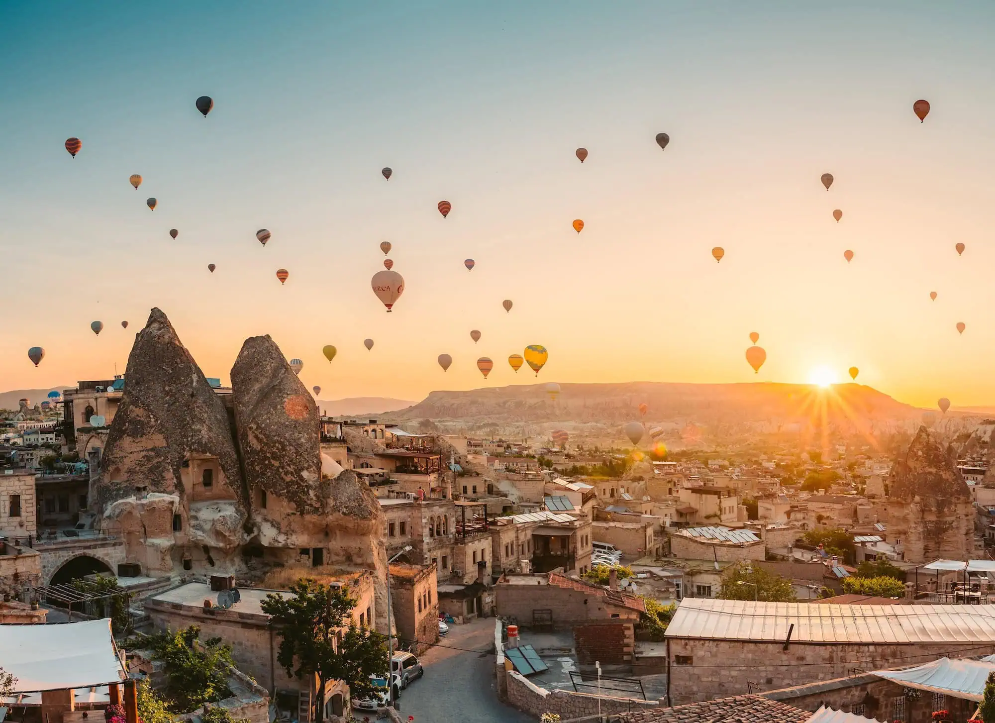 Colorful hot air balloons floating above Cappadocia's fairy chimney rock formations at sunrise