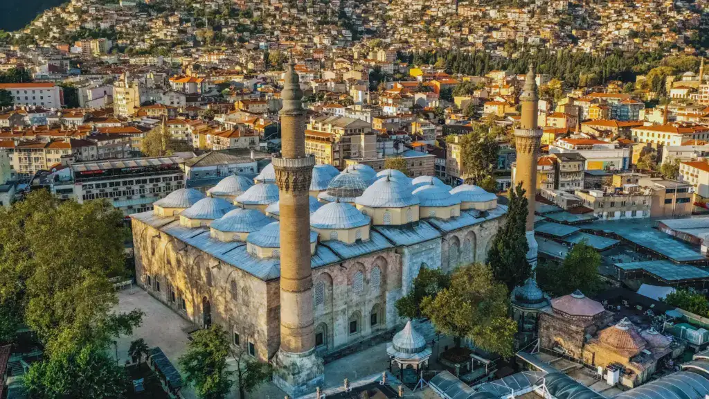 Bursa Grand Mosque (Ulu Cami) with multiple domes and twin minarets surrounded by dense urban buildings, Bursa