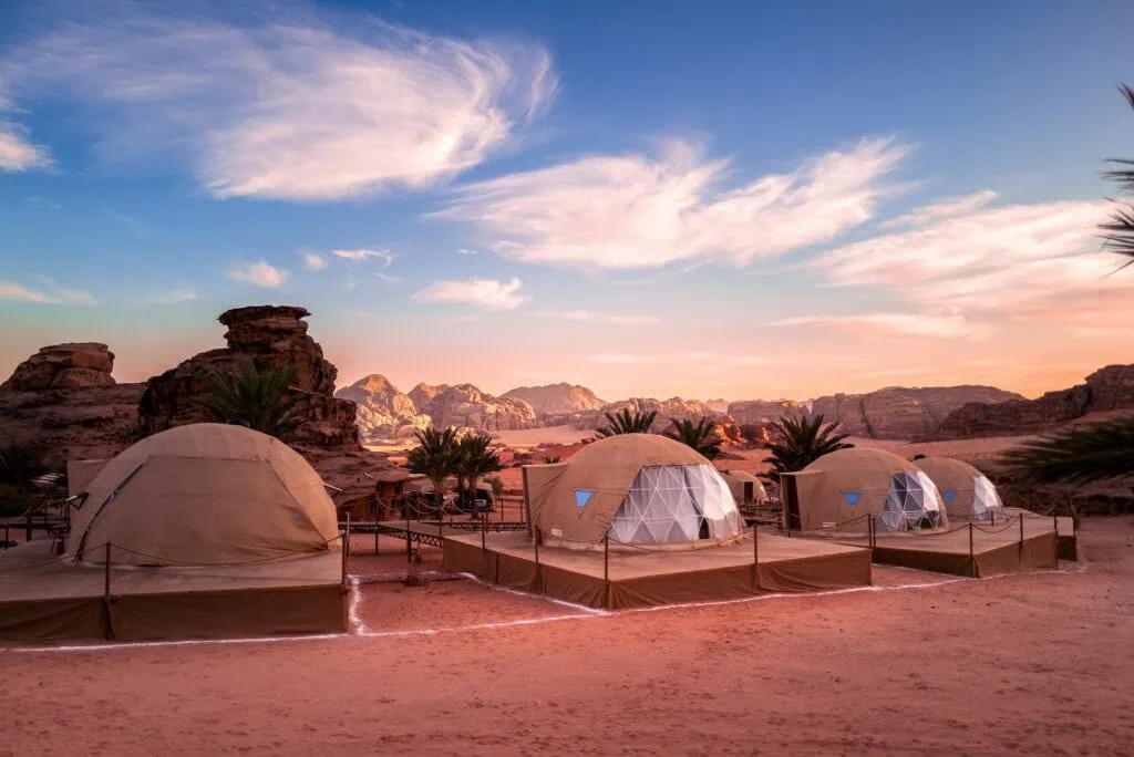 Geodesic bubble domes at a luxury glamping camp in Wadi Rum protected area, Jordan — semi-transparent dome tents set against the red sandstone valleys, designed for stargazing from the bed at night