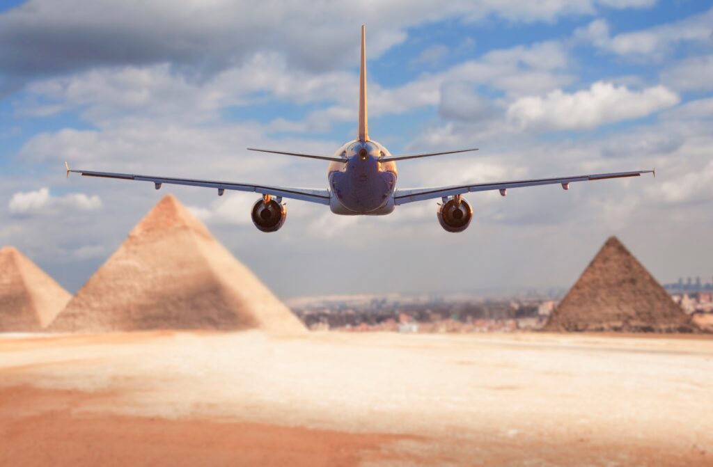 commercial passenger plane flies towards the Giza pyramids concept of travel to Egypt