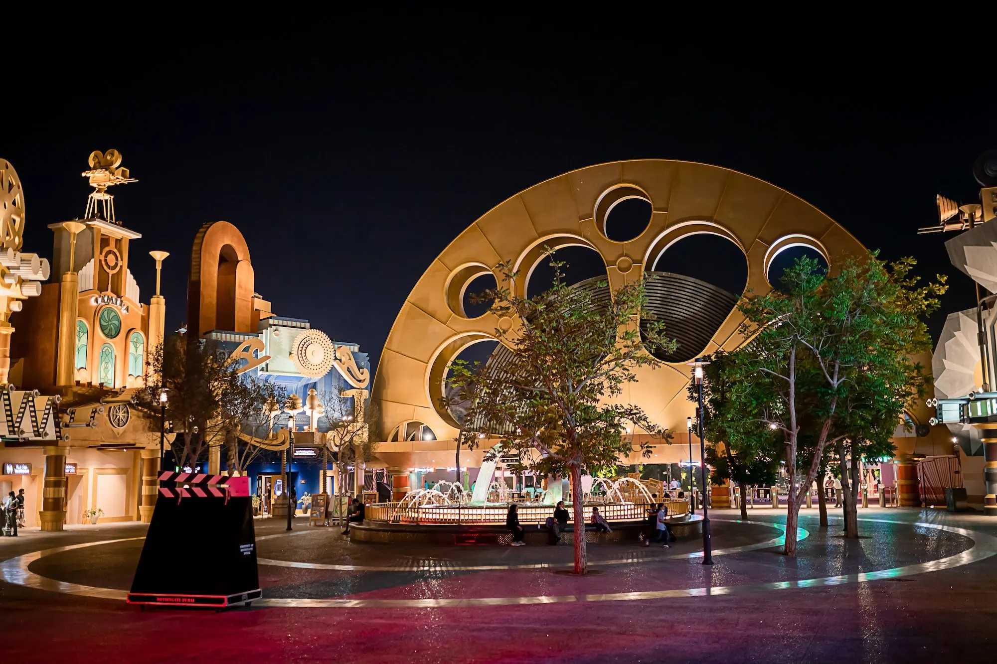 Illuminated film reel entrance archway to Motiongate Dubai theme park at night
