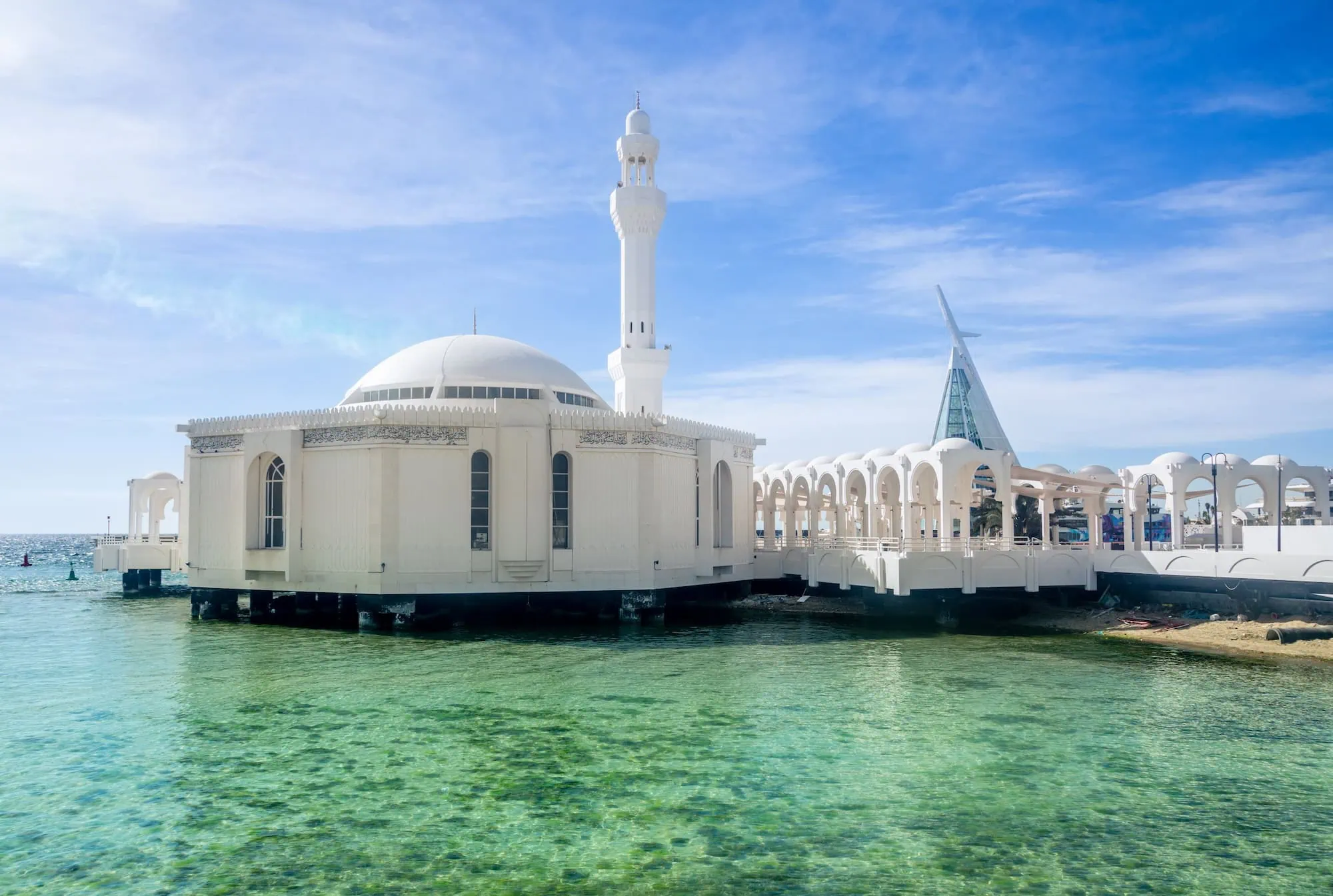 The Al Rahma Mosque (Floating Mosque) on the Corniche in Jeddah, Saudi Arabia — white-domed mosque built on stilts over the Red Sea, appearing to float on the water at high tide