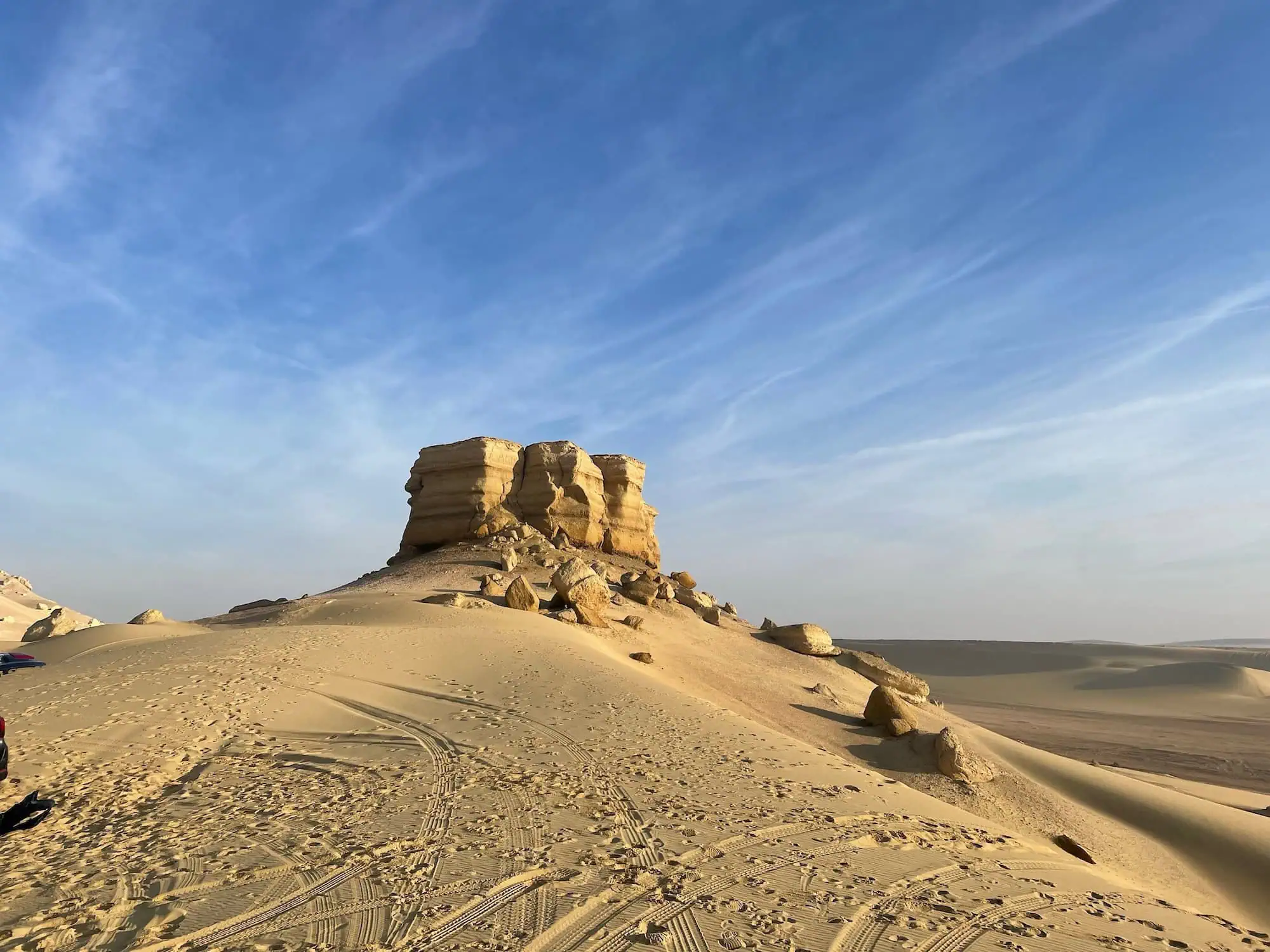 White rock formations in desert landscape with tire tracks
