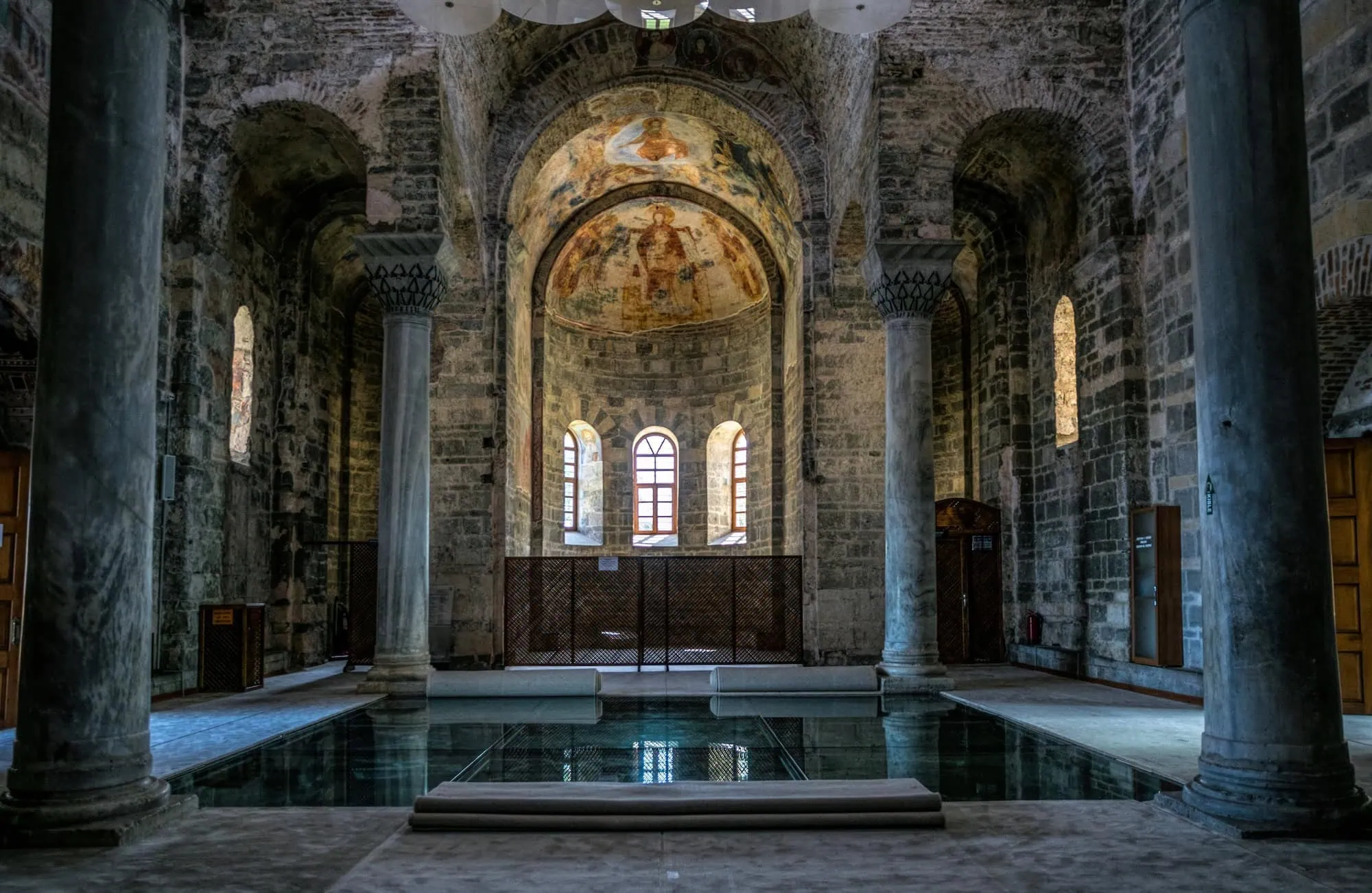 Interior view of Hagia Sophia in Istanbul, Turkey — Byzantine stone arches, marble columns, and surviving Christian-era mosaics beneath the central dome, originally built in 537 AD under Emperor Justinian
