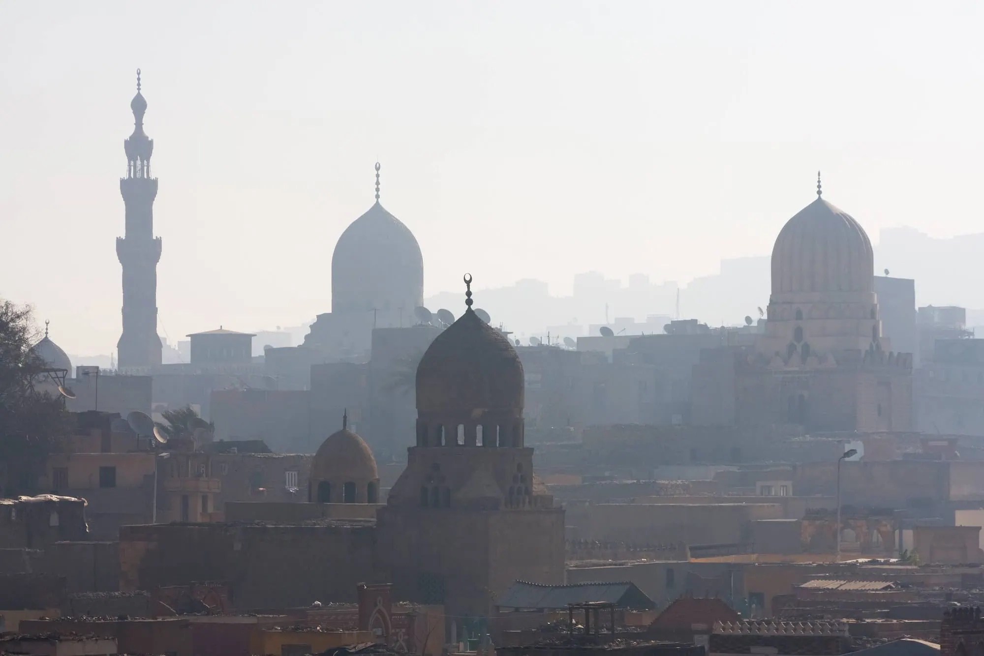 View across the medieval skyline of Islamic Cairo, Egypt — traditional mosque domes, minarets, and madrasas of the UNESCO-listed Historic Cairo