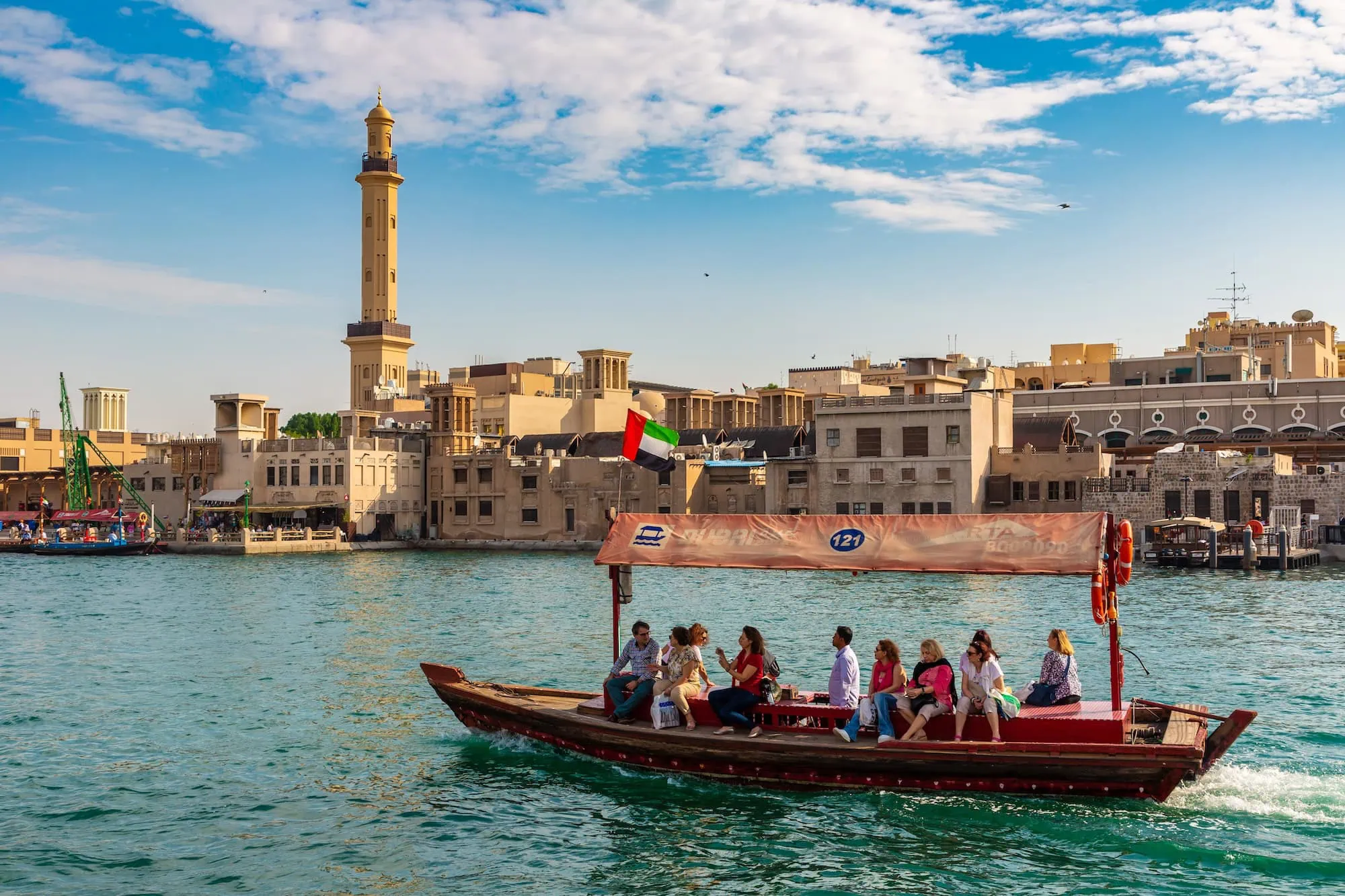 Traditional wooden abra water taxi with passengers sailing on Dubai Creek