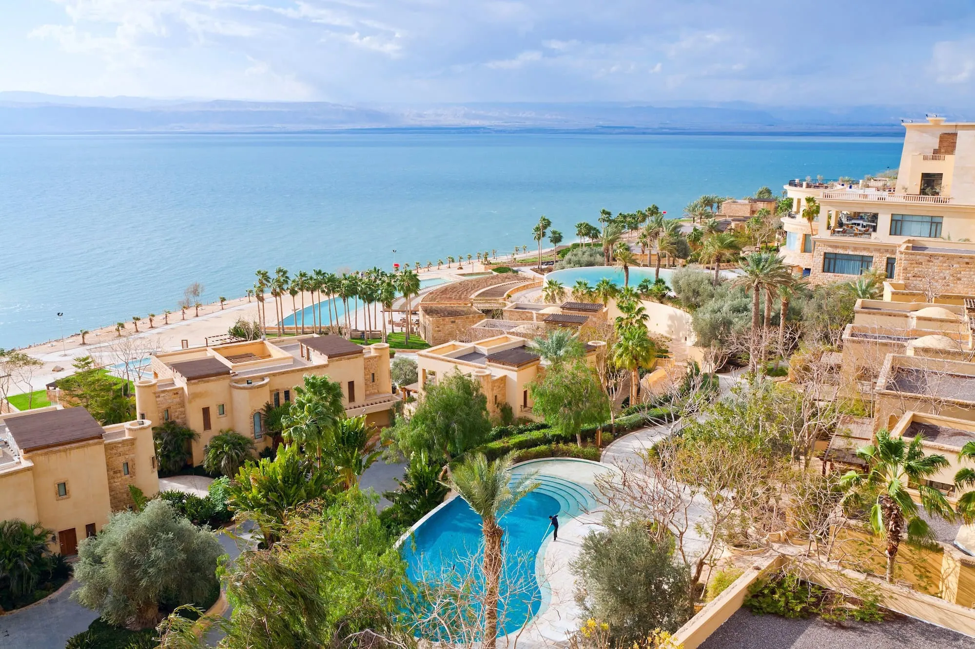 Aerial view of luxury resort complex on Dead Sea coast with turquoise waters and mountains