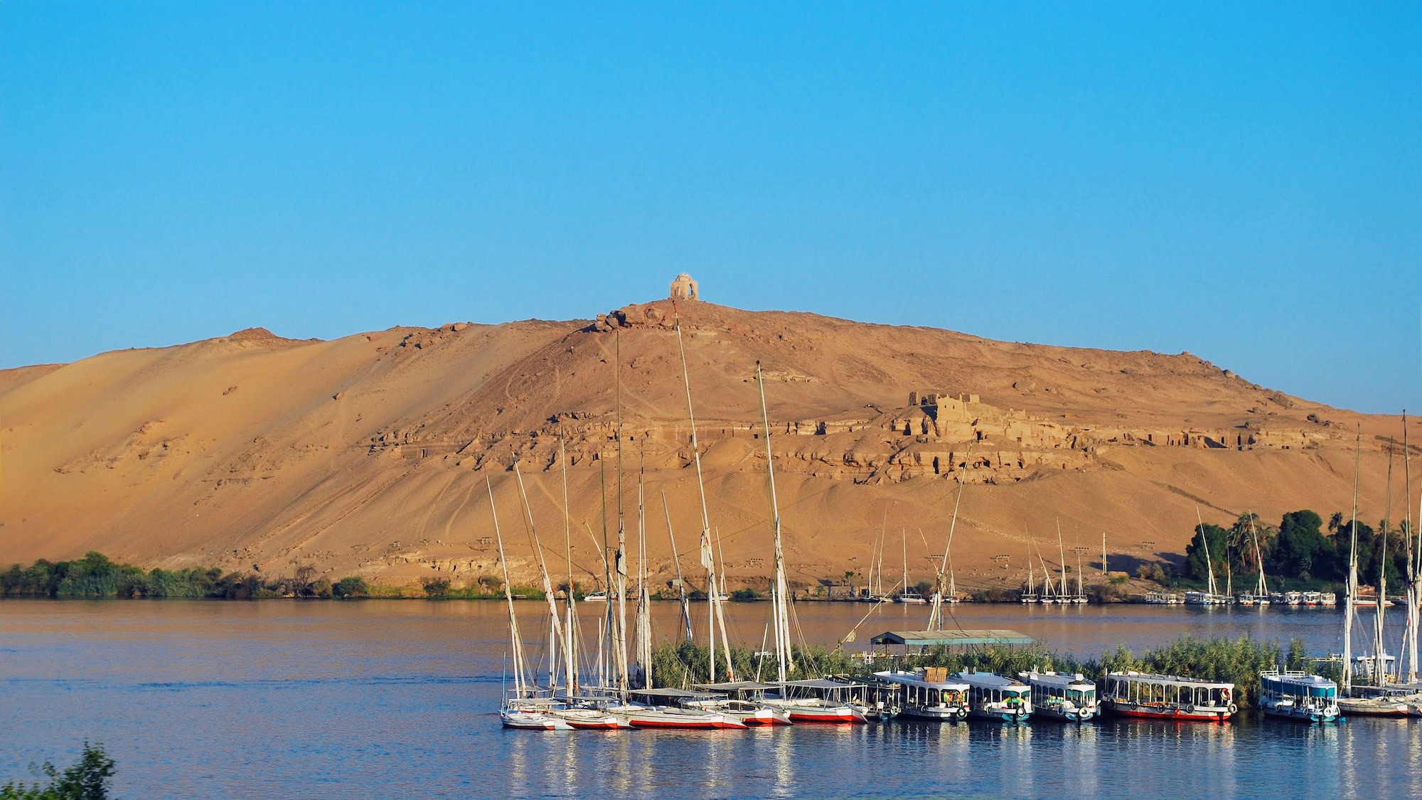 Ancient tombs carved into desert hills overlooking the Nile River at Aswan, Egypt