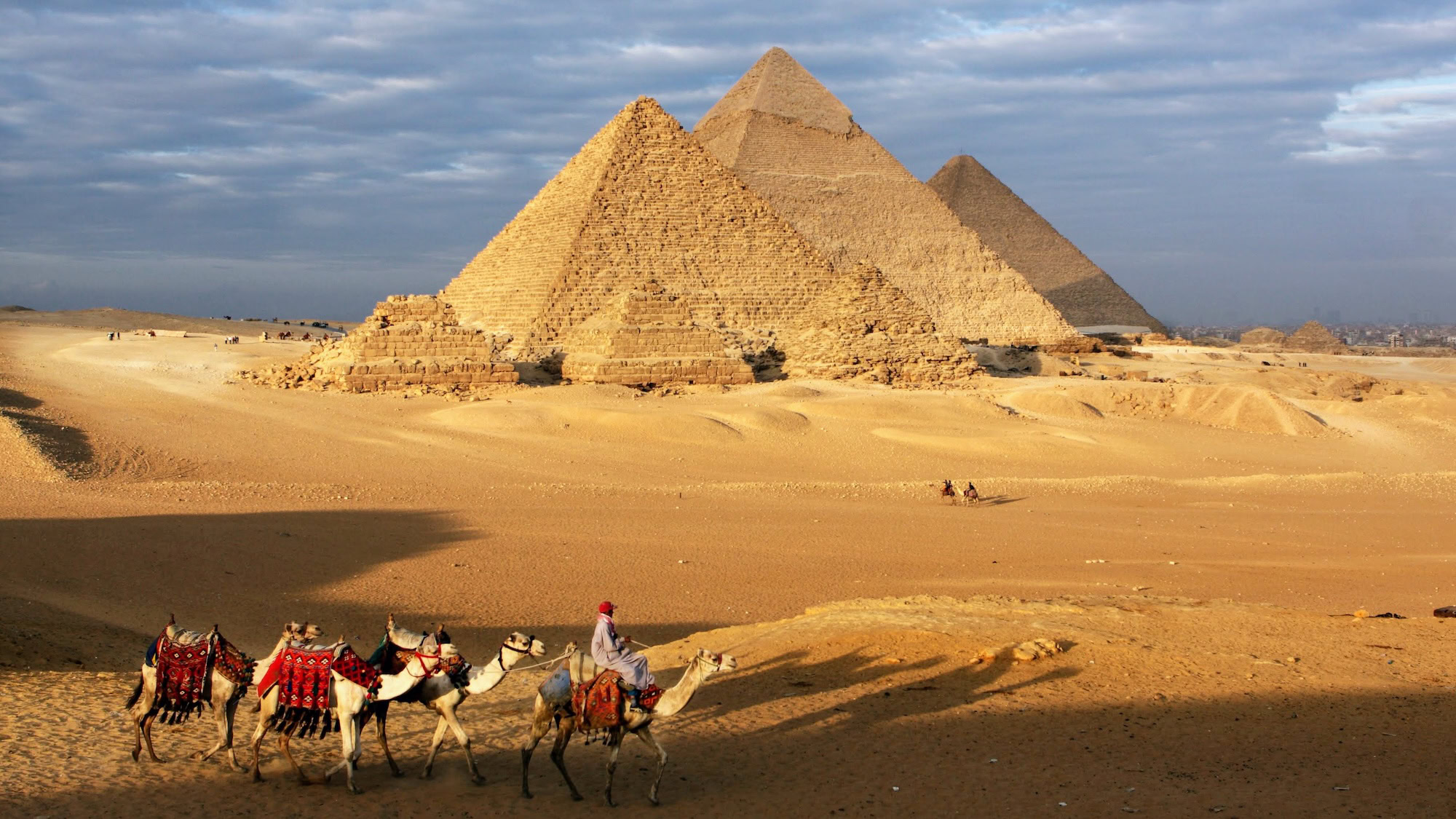Pirámides de Giza con camellos bajo cielo nublado en el desierto egipcio