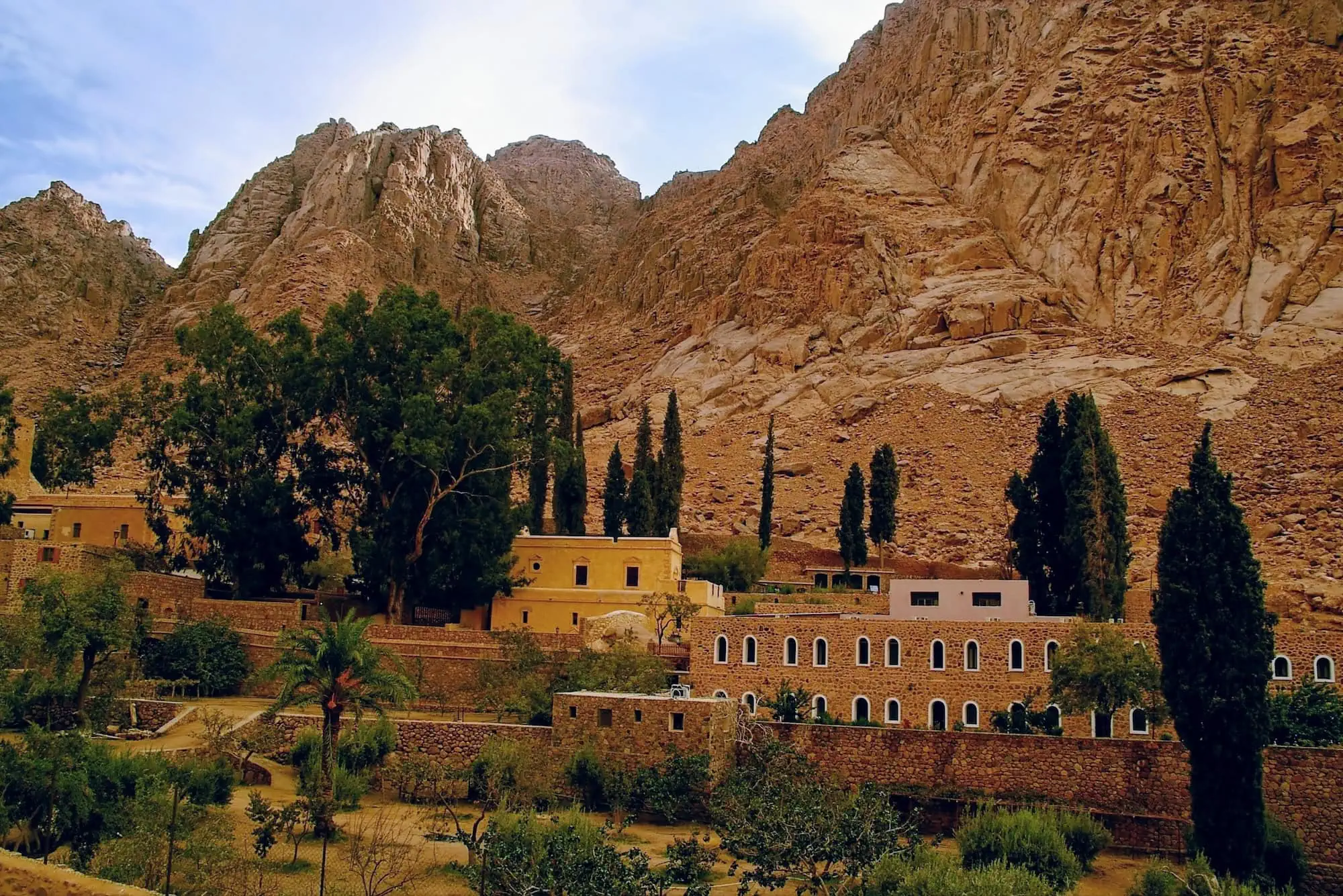 Panoramic view of Saint Catherine's Monastery at the base of towering desert mountains in Egypt's Sinai Peninsula