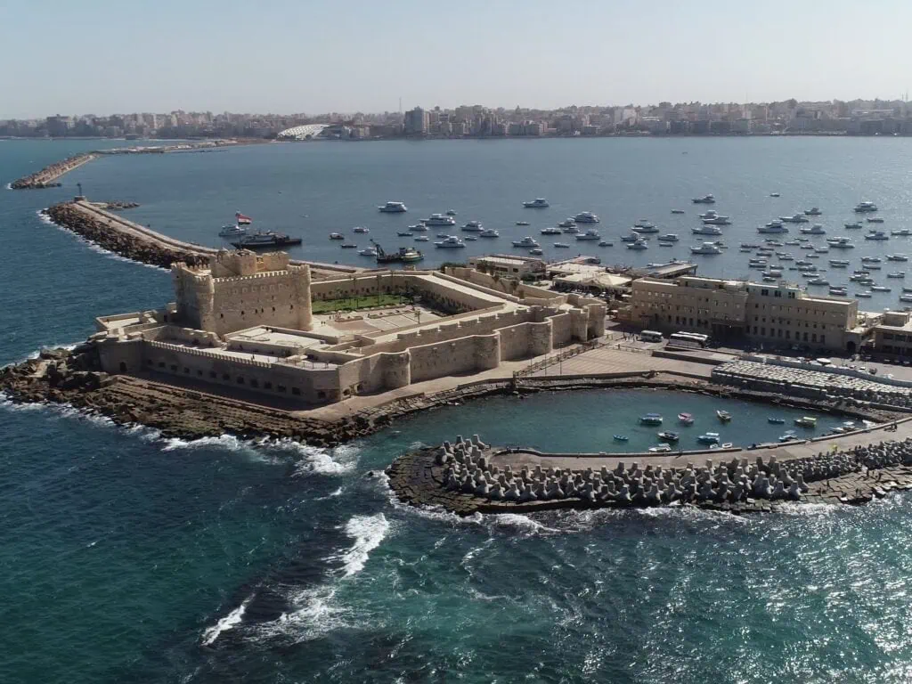 Aerial view of the 15th-century Citadel of Qaitbay on the Pharos peninsula in Alexandria, Egypt — Mamluk-era fortress built in 1477 directly on the foundation of the ancient Pharos lighthouse, with the Mediterranean Sea and the eastern harbour visible