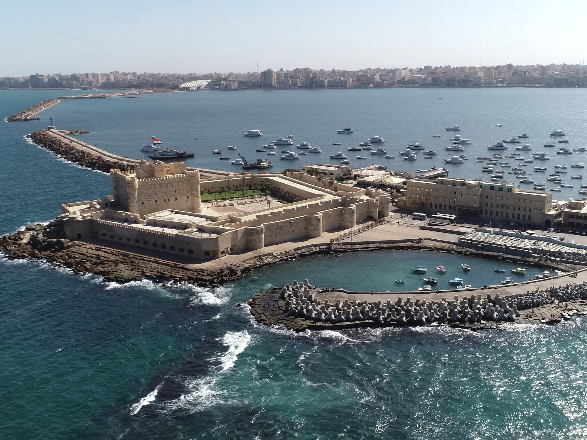 Aerial view of Qaitbay Citadel fortress on Alexandria's Mediterranean coastline with harbor and boats