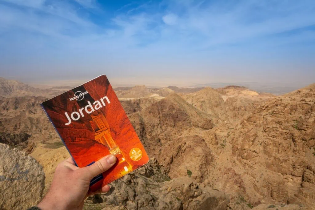 Travel guide book placed against mountainous desert landscape in Petra Wadi Musa
