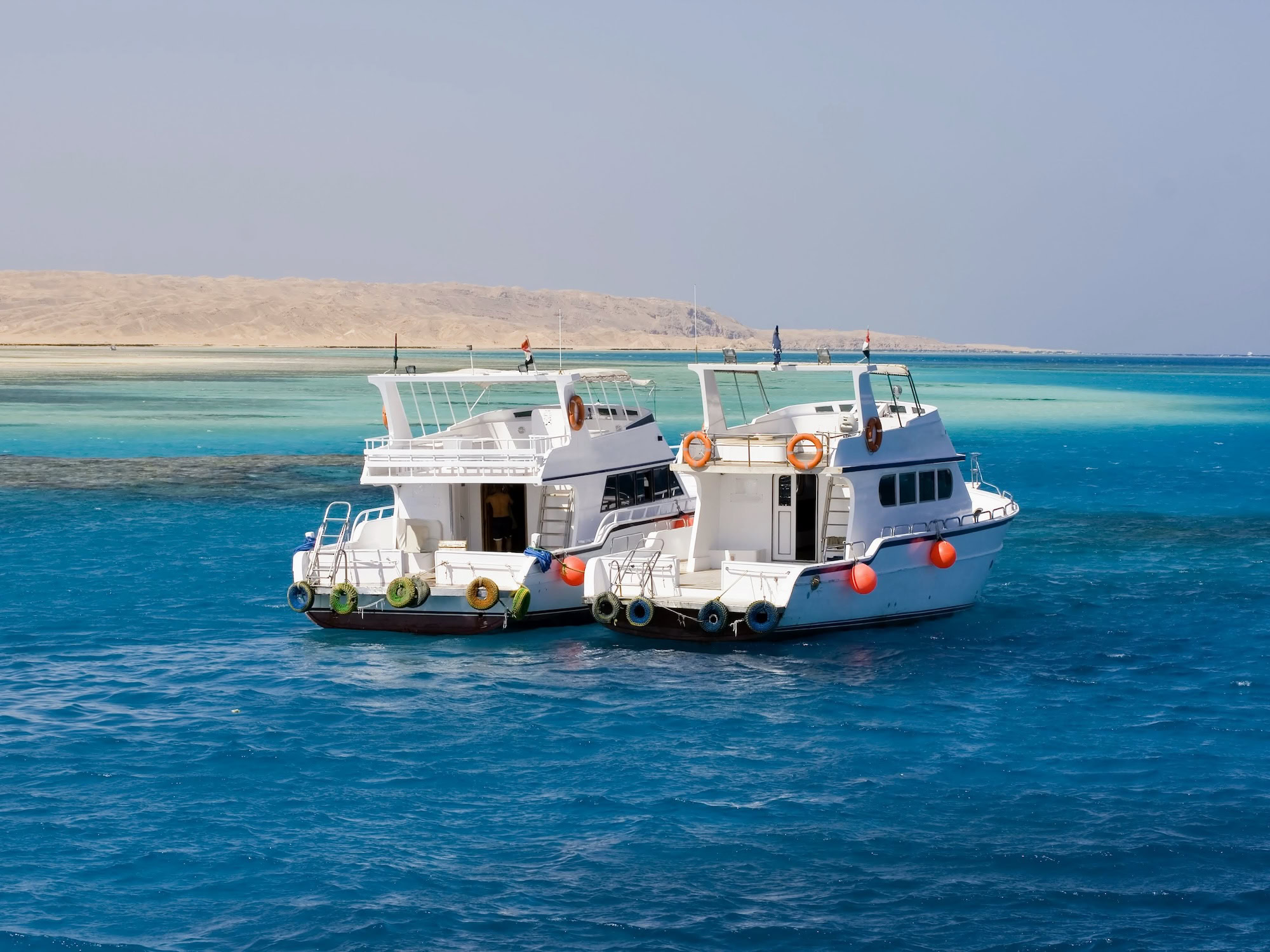 Yacht anchored in clear Red Sea waters with coral reef visible below