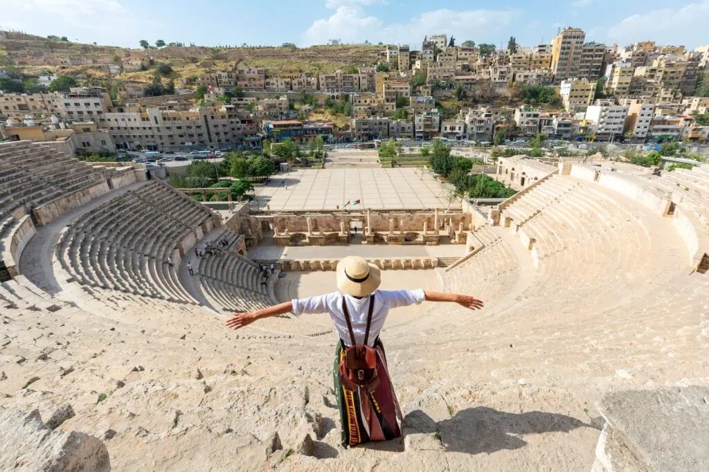 A visitor at the 2nd-century Roman Theatre in downtown Amman, Jordan — 6,000-seat theatre carved into the hillside, built during Emperor Antoninus Pius's reign (138–161 AD), still in use for cultural performances today