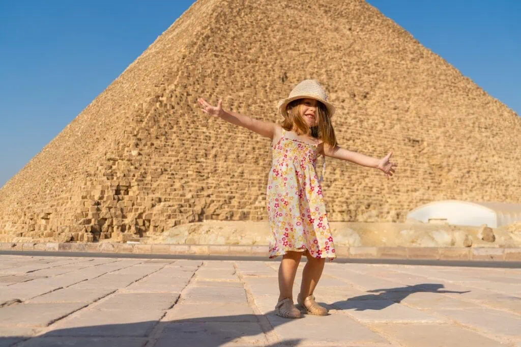 Little girl dancing in front of the Cheops pyramid on the Giza plateau