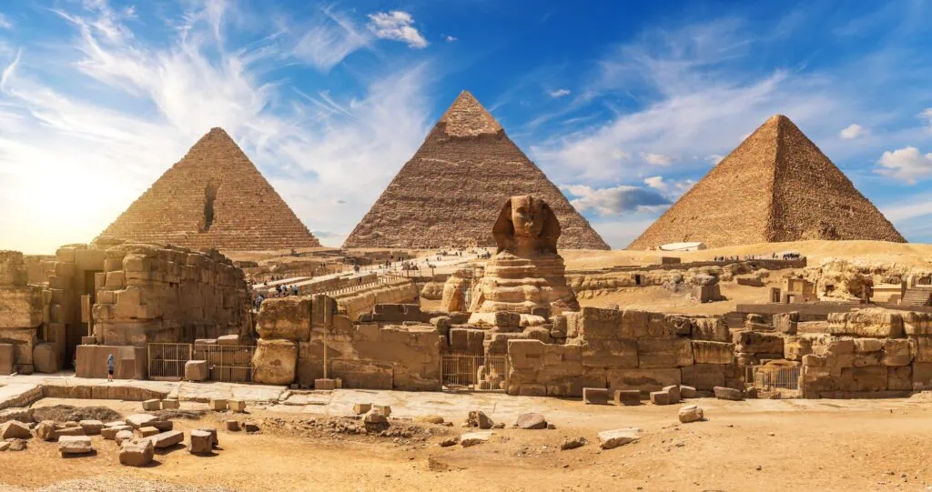 The Great Sphinx of Giza in the foreground with the Great Pyramid of Khufu and the Pyramid of Khafre rising behind it on the desert plateau under a clear sky. Egypt Shore Excursions.