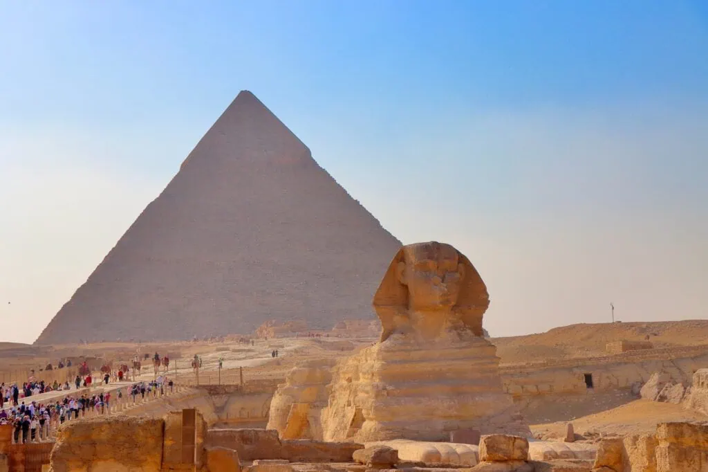The Great Pyramid of Khufu and the Great Sphinx of Giza rising from the desert plateau on the western edge of Cairo, photographed under clear sky.