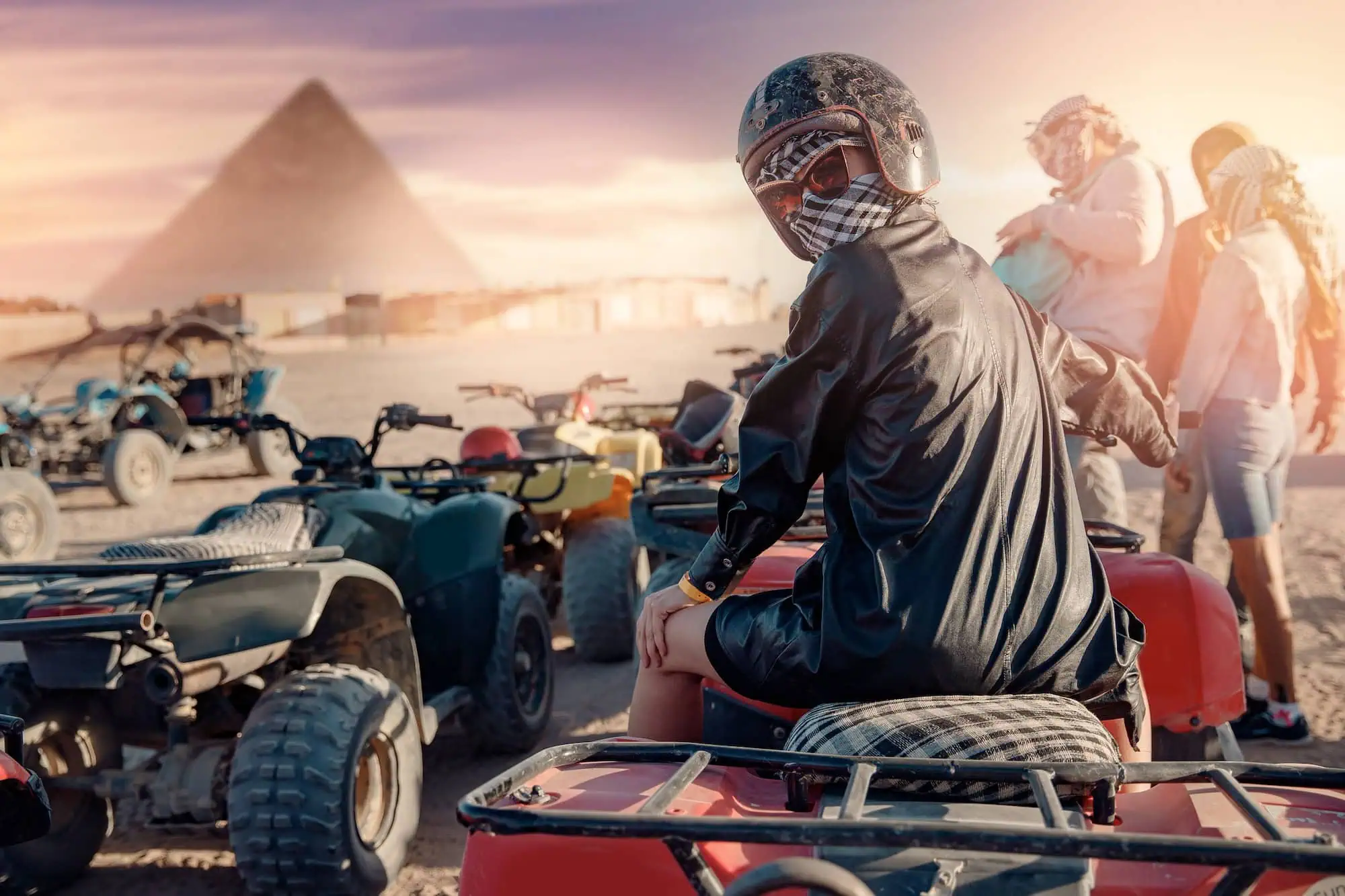 Turistas en quad bikes explorando las pirámides de Giza en el desierto egipcio