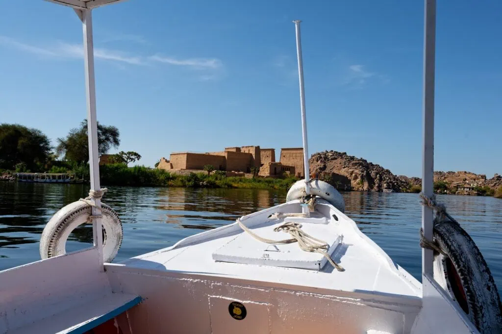 Small ferry approaching the iconic Philae Temple across the calm waters of Lake Nasser