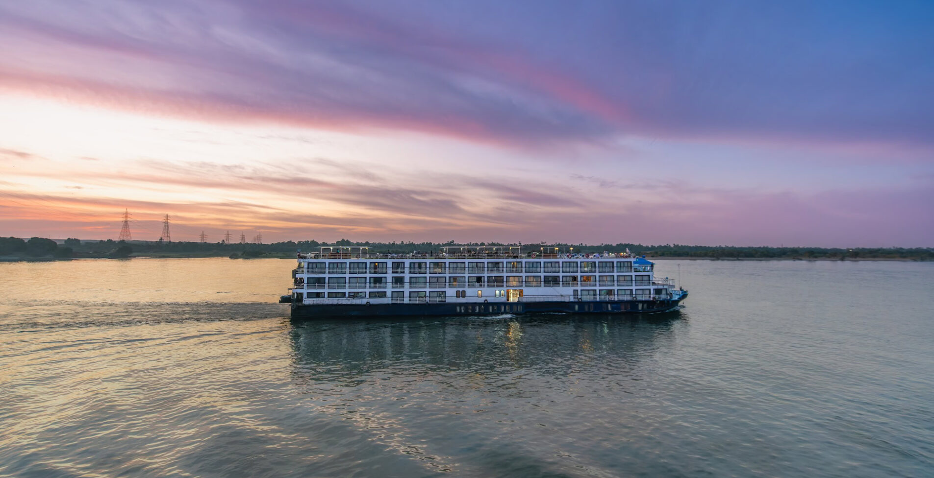 A large cruise ship glides along the tranquil Nile River near Esna Lock Aswan Egypt at dusk 1905x976 crop 51 60