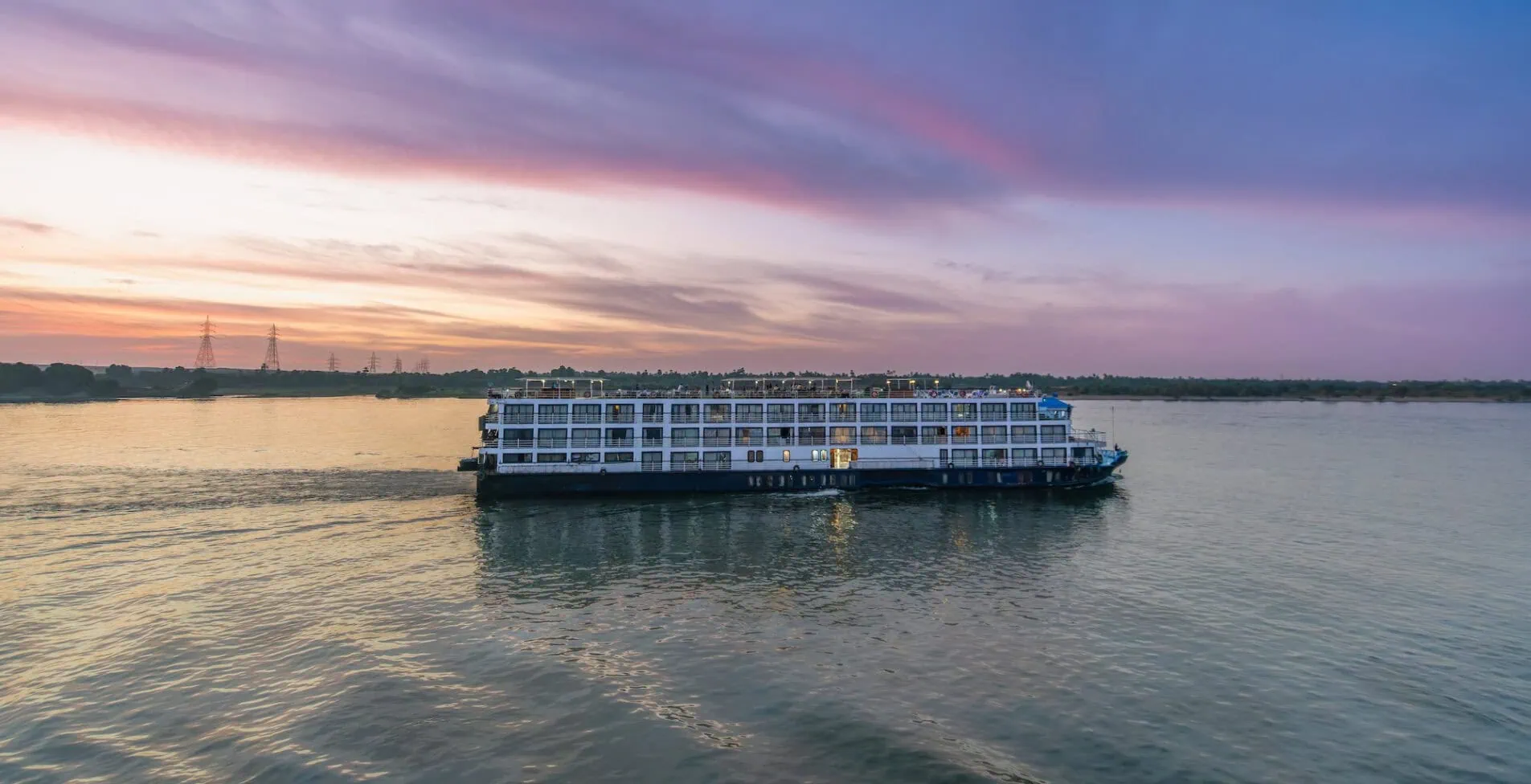 A large cruise ship glides along the tranquil Nile River near Esna Lock Aswan Egypt at dusk 1905x976 crop 52 71
