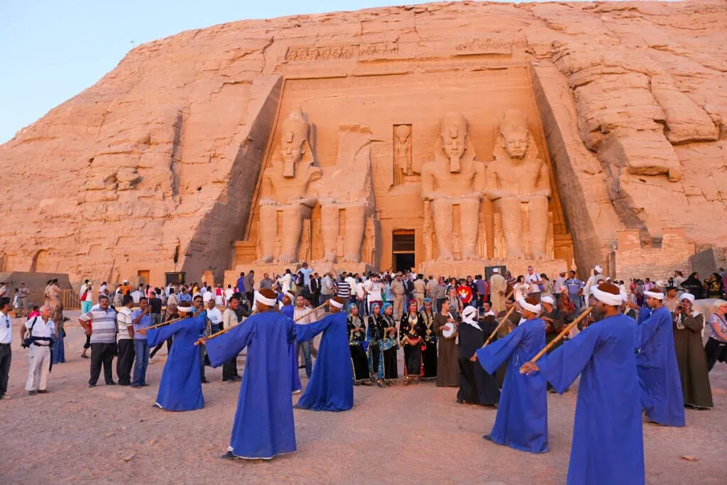 Traditional dancers performing near the rock-cut temple as tourists watch during the sun festival, Abu Simbel Temple, Abu Simbel