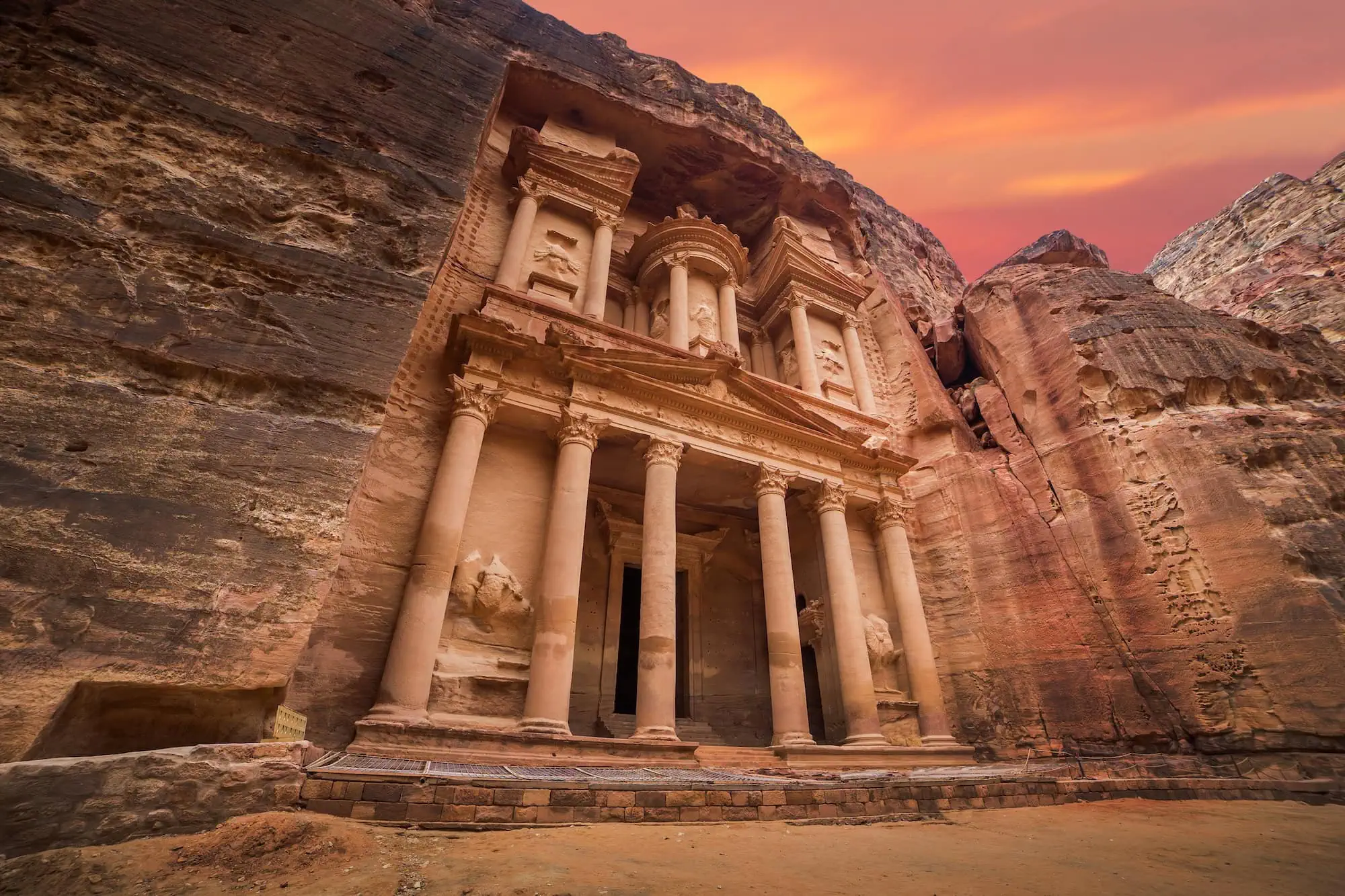 The iconic Treasury facade carved into rose-red sandstone cliffs in Petra, Jordan during golden hour