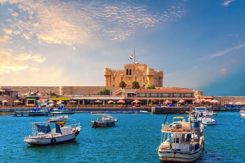 Small boats moored in the harbor with the stone fortress on the waterfront, Citadel of Qaitbay Alexandria