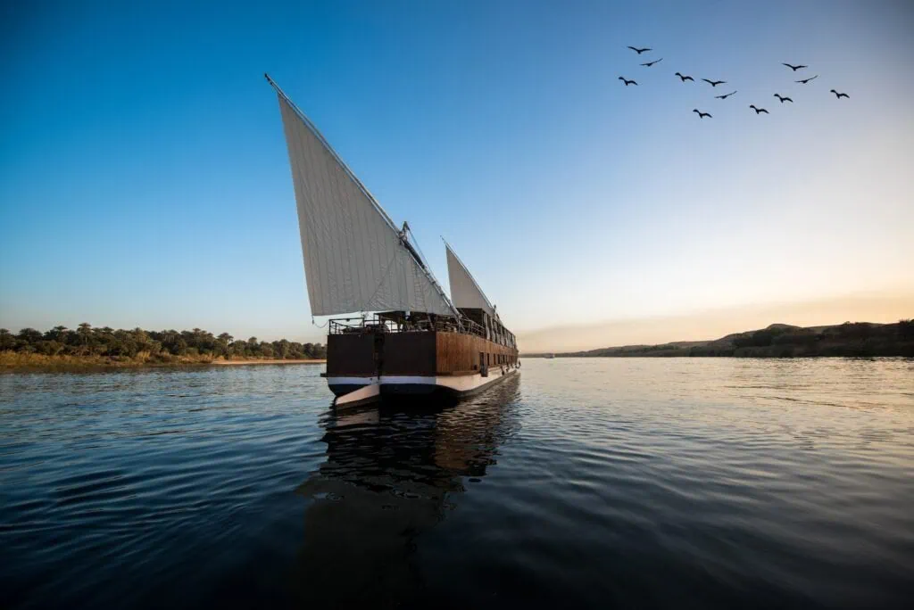 Traditional twin-mast Dahabiya sailing the Upper Nile under lateen rig and wind power, on a vessel design unchanged since 19th-century Nile travellers, photographed on the Esna–Aswan stretch.