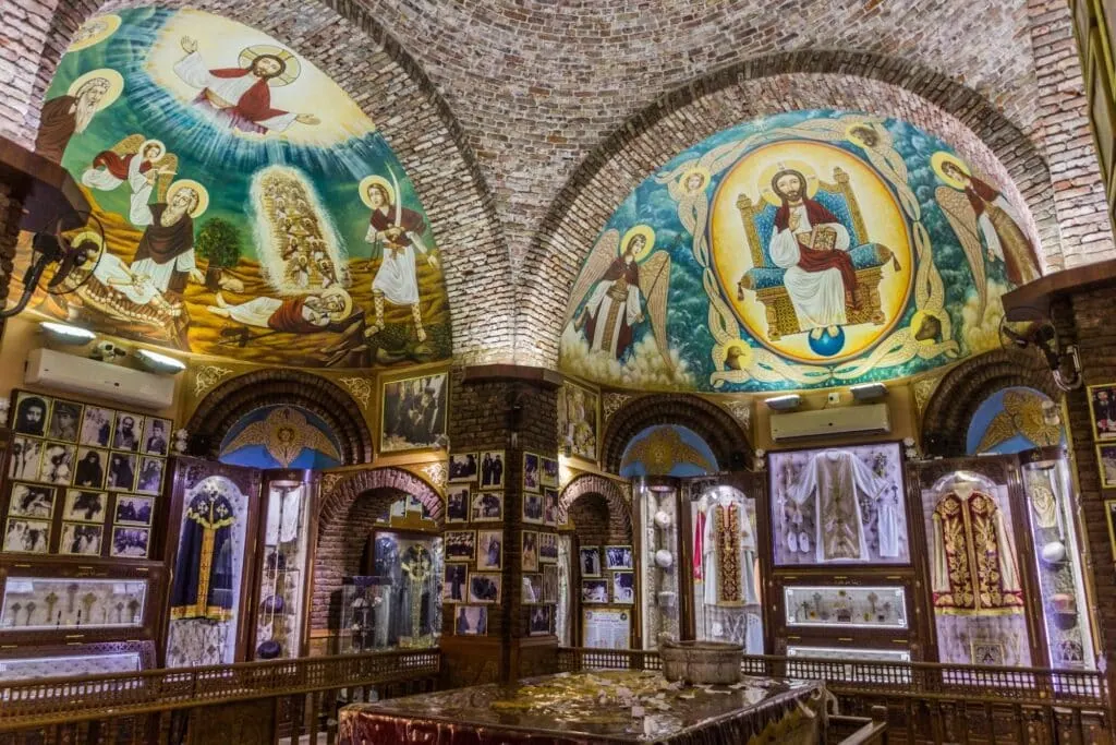 An interior view with stone arches, columns, and hanging Coptic icons inside Saint Pishoy Monastery, Wadi El Natrun