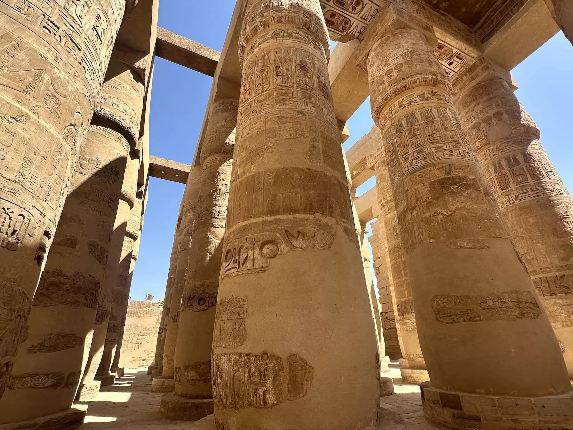 he massive carved stone columns of the Great Hypostyle Hall at Karnak Temple, covered in hieroglyphic inscriptions, Luxor, Egypt.