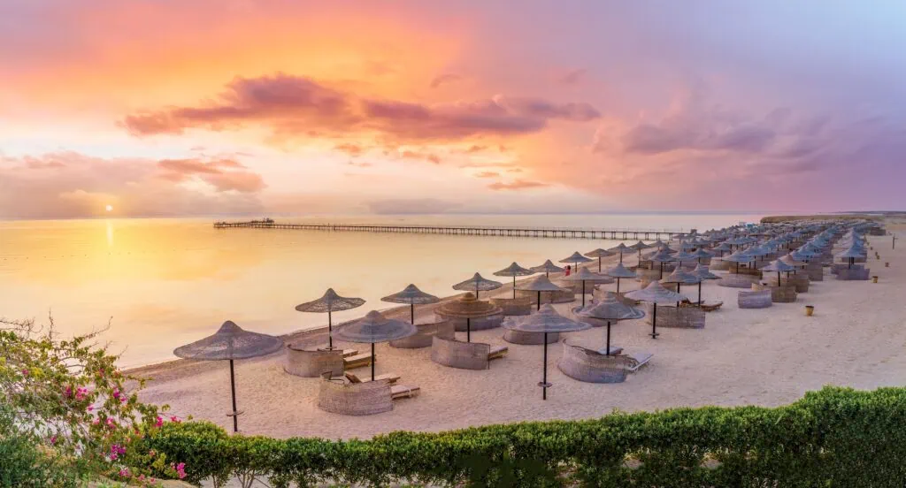 Three Corners Fayrouz Beach Resort at sunrise in Marsa Alam, with palm-fringed pool and beach buildings on Egypt's southern Red Sea coast