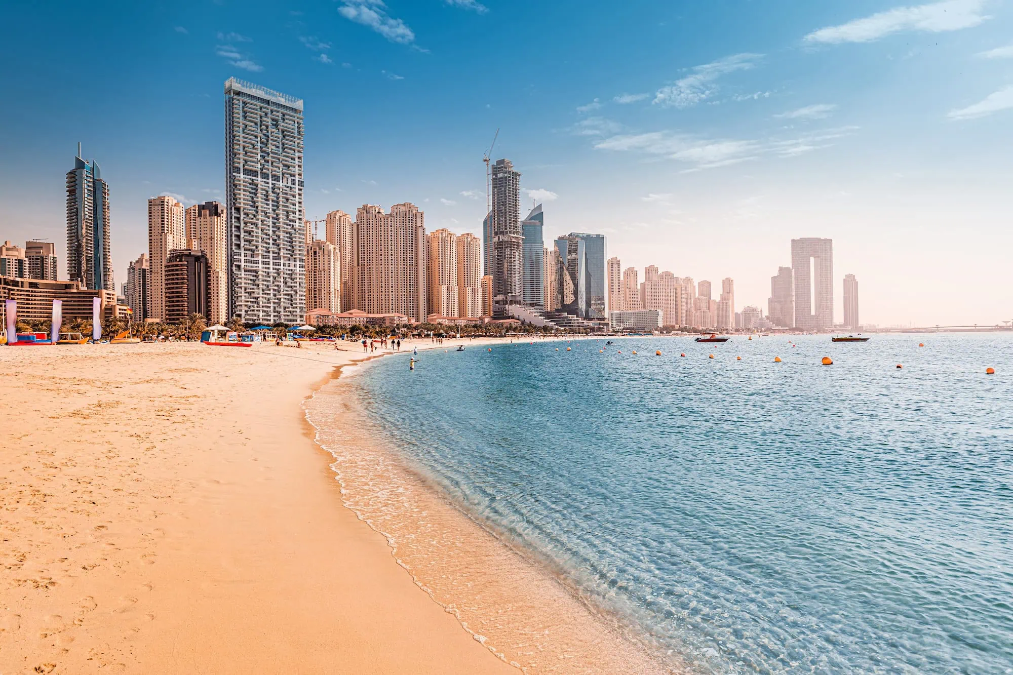 Sandy beach with turquoise water and Dubai Marina skyline in background