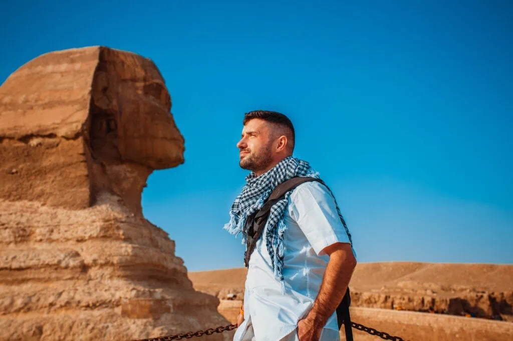 Male tourist pretends to kiss the sculpture of Giza, Egypt