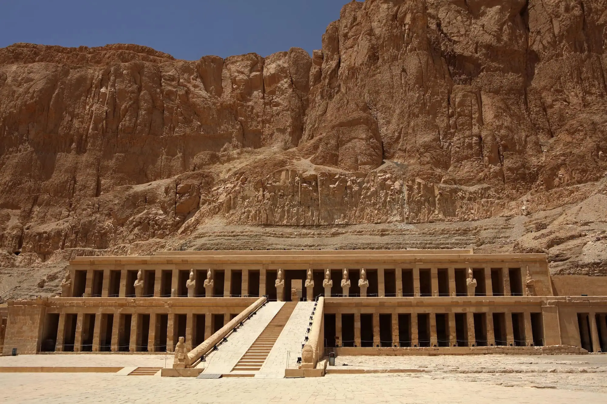 Temple of Queen Hatshepsut with limestone columns, statues, and terraced architecture against desert cliffs