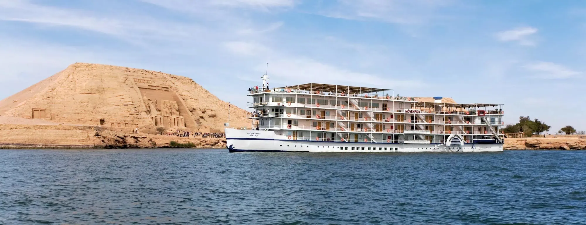 Tourist cruise boat docked near Abu Simbel Temple with visitors exploring the ancient Egyptian site
