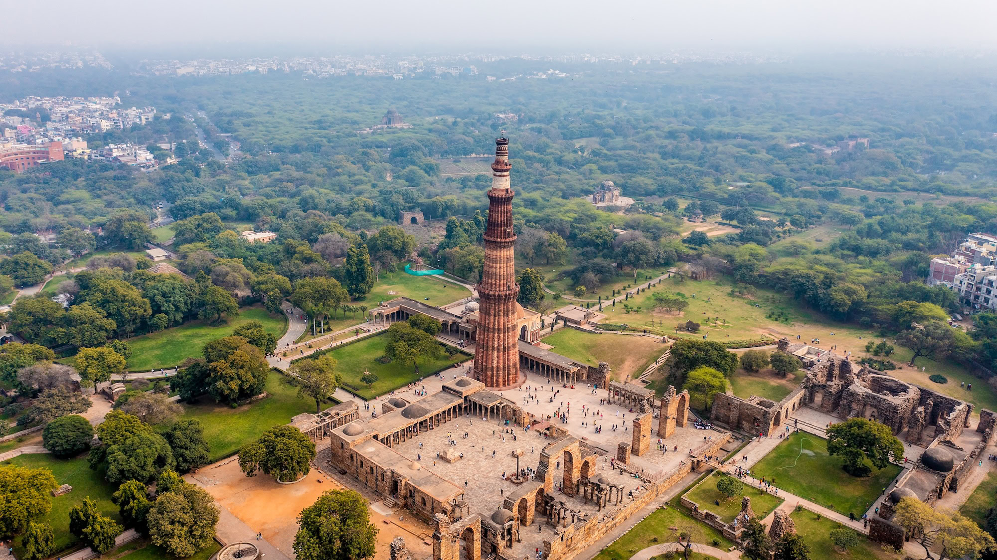 Vista aérea del complejo Qutub Minar en Delhi mostrando el minarete, mezquita y ruinas históricas