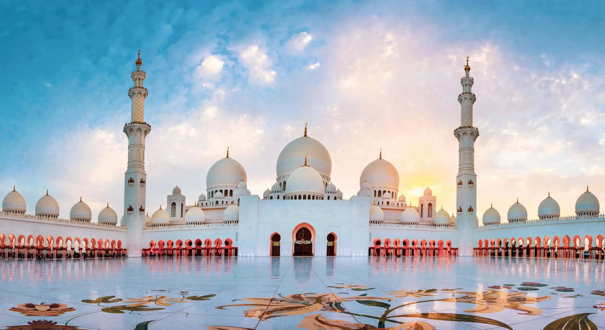 Sheikh Zayed Grand Mosque with white domes and minarets at sunset in Abu Dhabi