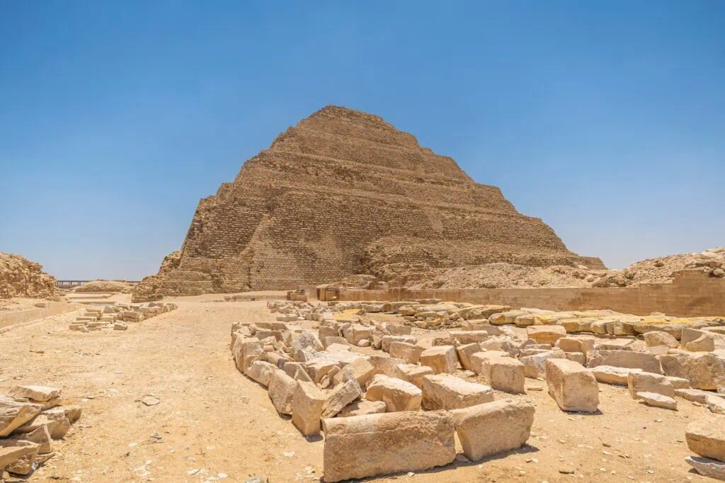 Terraced limestone pyramid rising above desert ruins in the Saqqara necropolis, Step Pyramid of Djoser, Saqqara