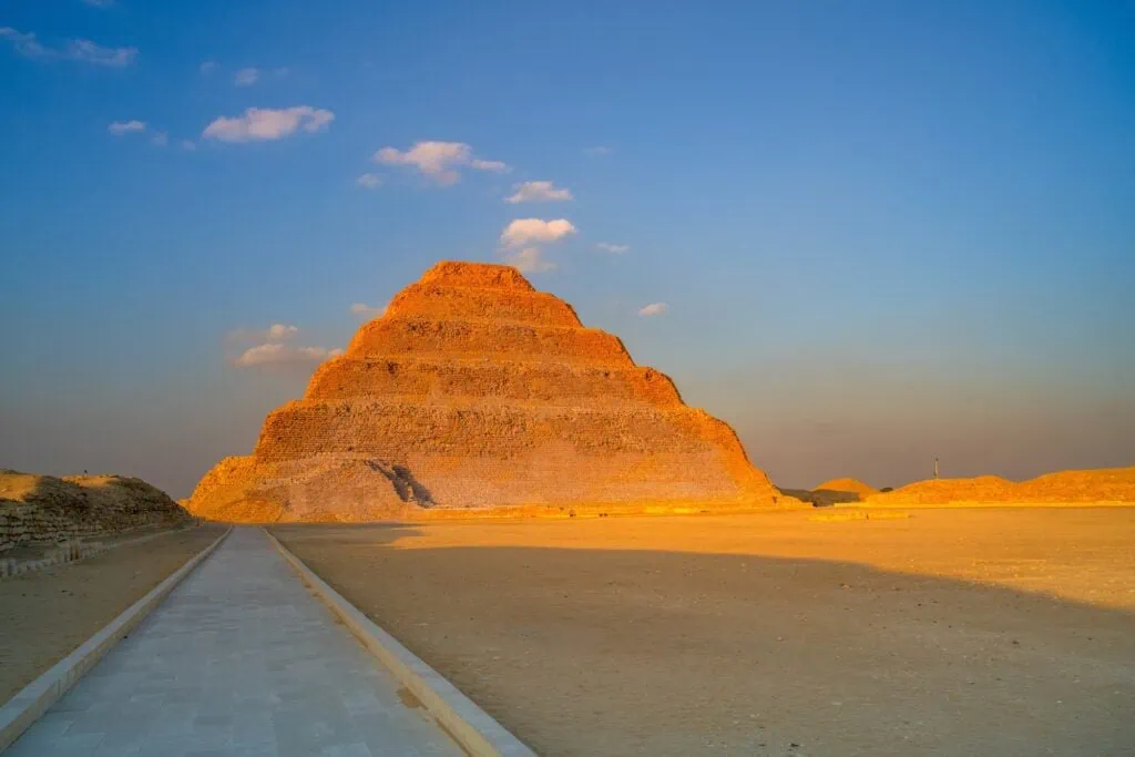 The six-tiered Step Pyramid of Djoser rising from the desert floor within the Saqqara necropolis complex south of Cairo, Egypt.