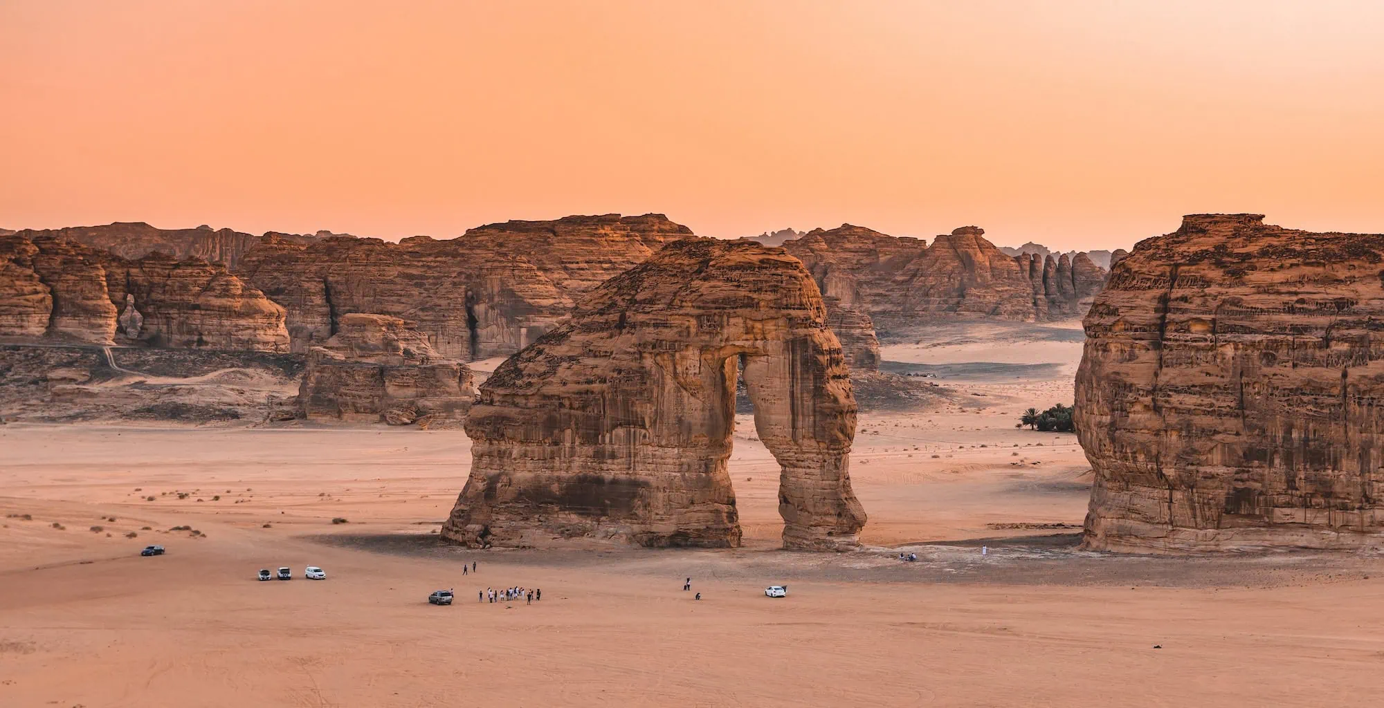 Elephant Rock (Jabal AlFil) in AlUla, Saudi Arabia — a free-standing sandstone formation eroded into the shape of an elephant, with visitors at its base for scale