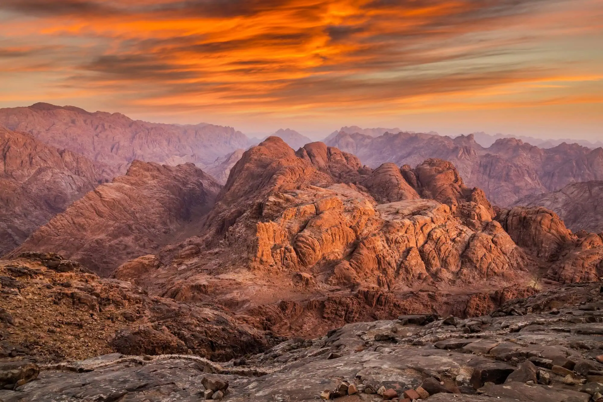 Stunning sunrise view from Mount Sinai showing dramatic orange-lit mountain landscape