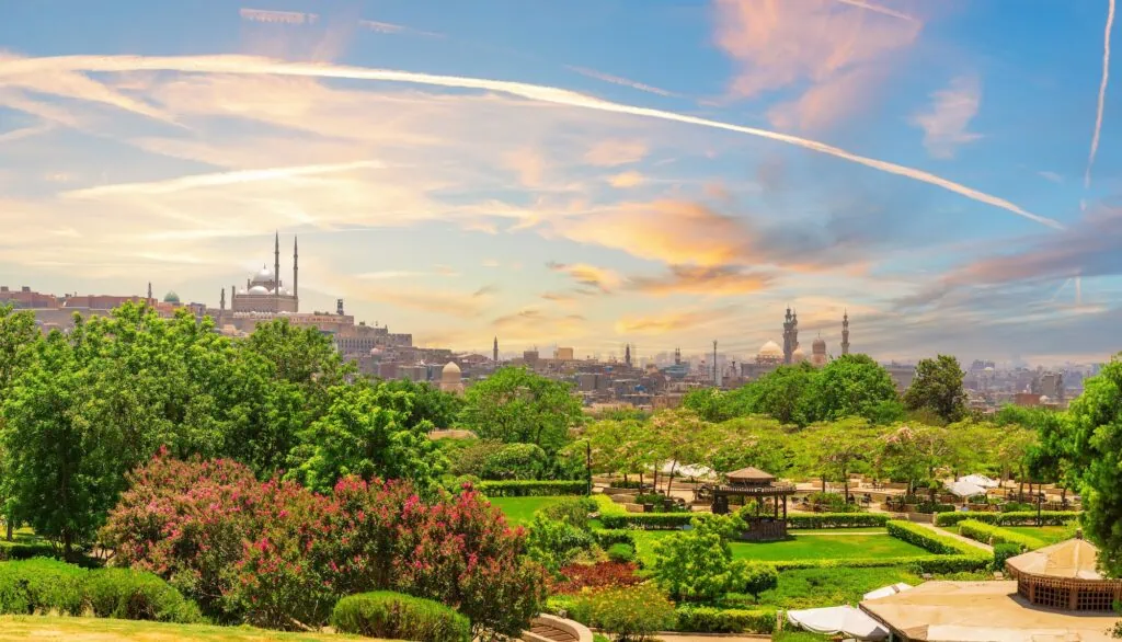 A landscaped view of Al-Azhar Park with green lawns and pathways and the Mosque of Muhammad Ali visible in the background, Cairo