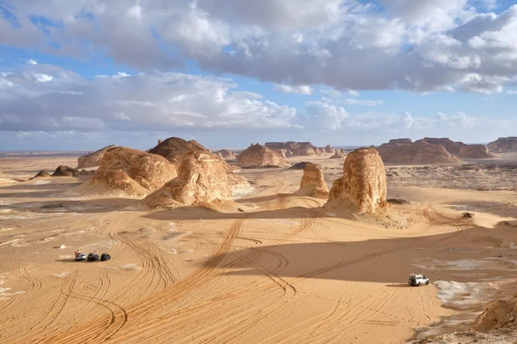 Four-wheel-drive vehicles among the white chalk rock formations of the White Desert protected area near Farafra in Egypt's Western Desert.