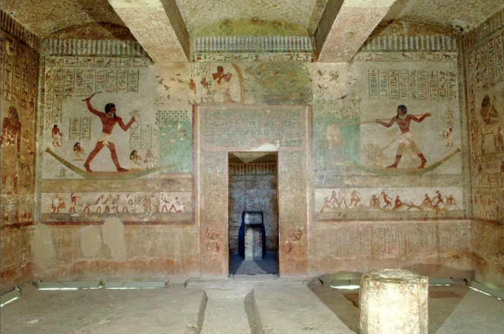 Painted wall reliefs and hieroglyphic inscriptions inside the Tomb of Khnumhotep II at Beni Hassan, showing scenes of daily life in Middle Kingdom Egypt, with the original colours largely intact.