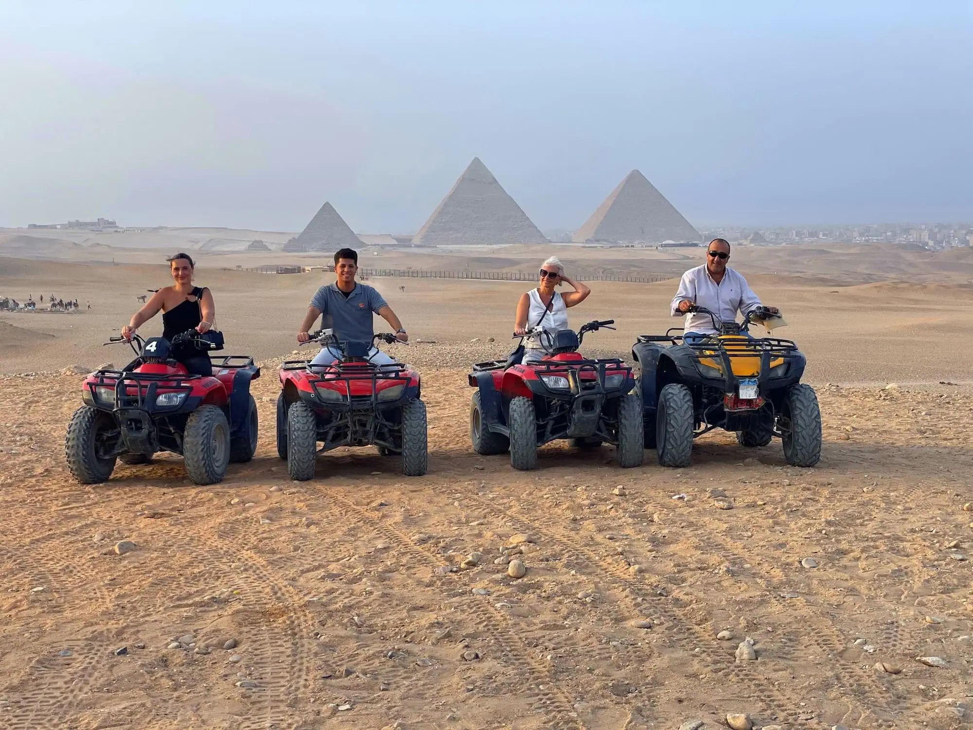 Tourists on quad bikes exploring the Pyramids of Giza in the desert