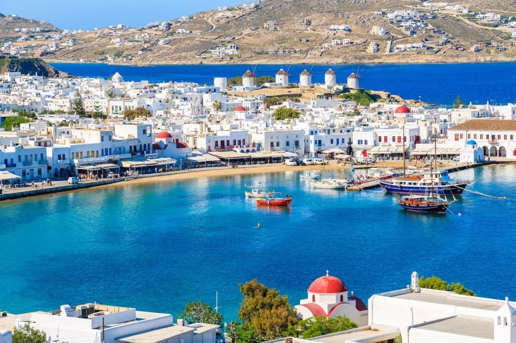 View of Mykonos old port in the Cyclades, Greece — traditional wooden caïques moored along the waterfront with whitewashed Cycladic buildings and bell towers behind - Egypt and Greece Tours