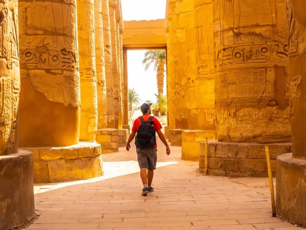 Young man walking among the hieroglyphic columns of Karnak Temple