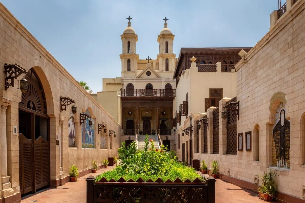 The decorated courtyard of the Hanging Church (Saint Virgin Mary's Coptic Orthodox Church) in Coptic Cairo, with mosaic walls and twin bell towers, Egypt.